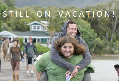 A horizontally flipped picture of the actor Matthew Fox being given a piggyback ride by the actor Jorge Garcia on the set of LOST with the caption STILL ON VACATION!.