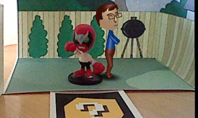 A picture of a Nintendo Mii version of Tylor Lilley posing in a diorama with a Strong Bad figure, taken with a Nintendo 3DS and AR card